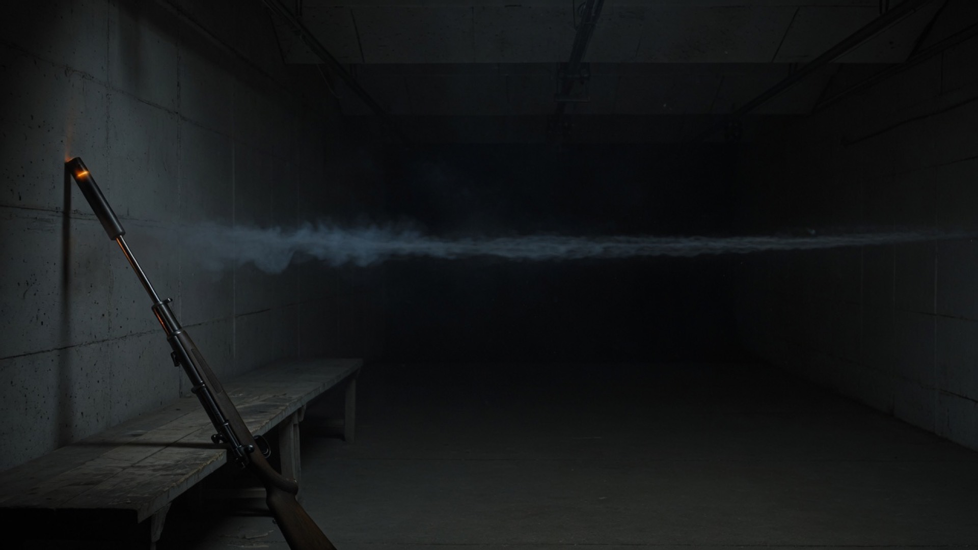 A rifle resting on a bench in a dark indoor range lane.
